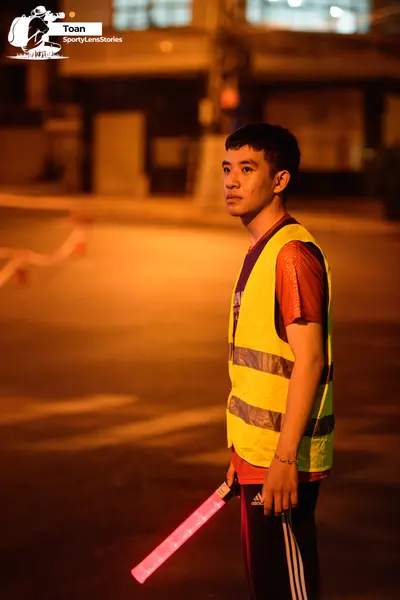 Marathon runner: Person 1: red jersey, yellow high-visibility vest, black pants with white stripe