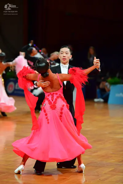 Dancesport competitor: Female dancer: bright pink Latin dance dress with red sequin embellishments on t