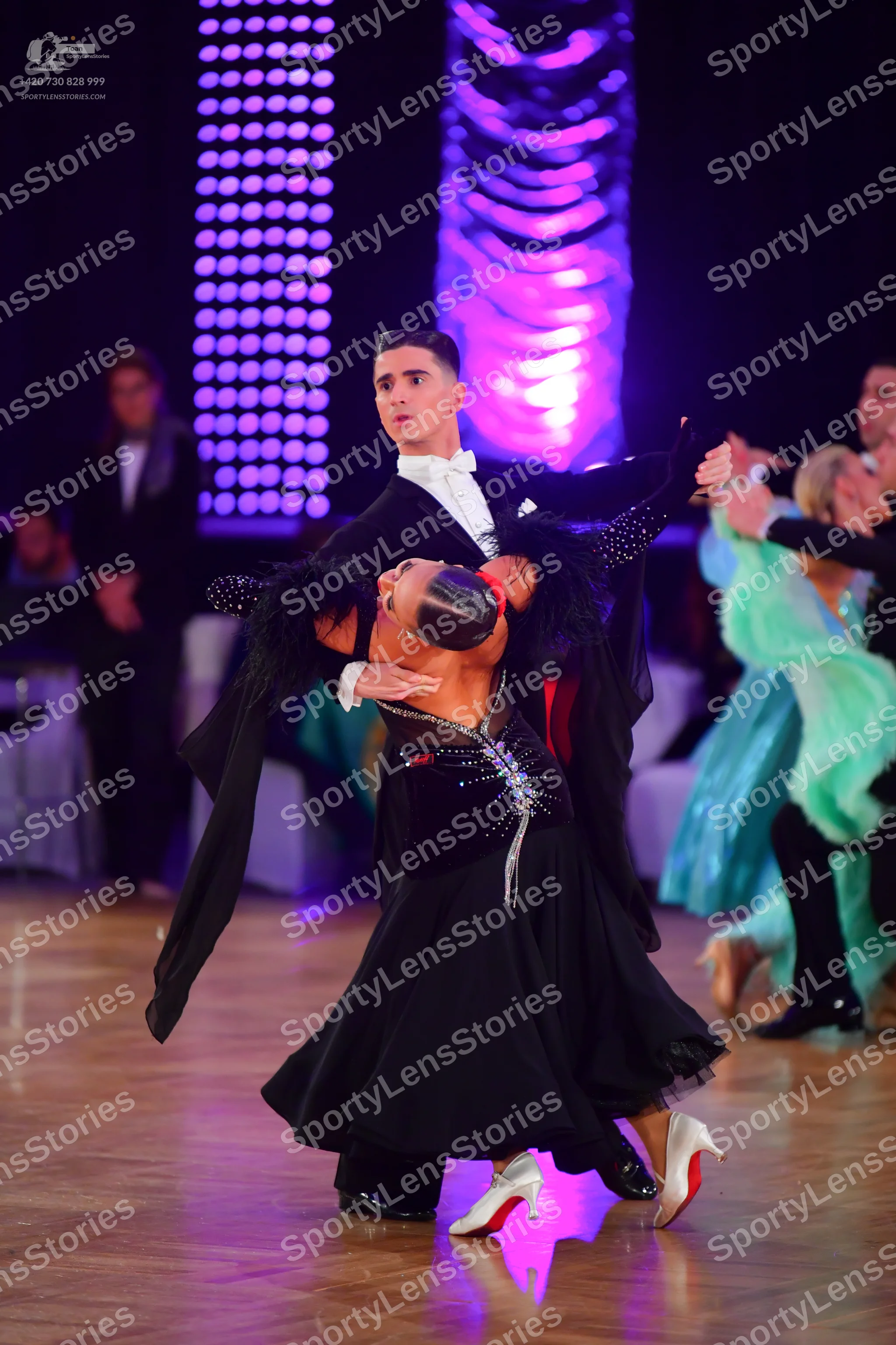 Dancesport competitor: Central male dancer: black suit with a white shirt and white bowtie