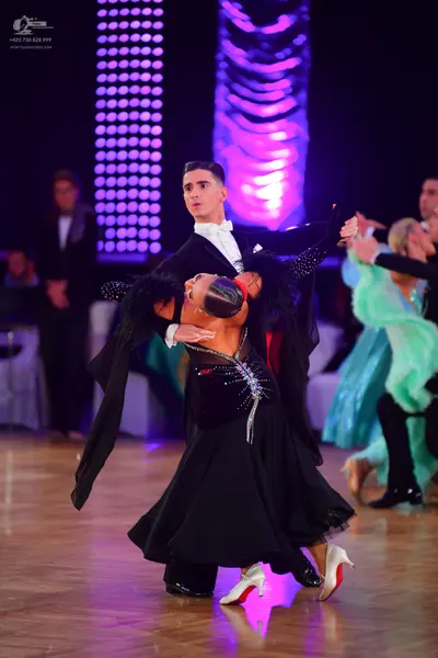 Dancesport competitor: Central male dancer: black suit with a white shirt and white bowtie