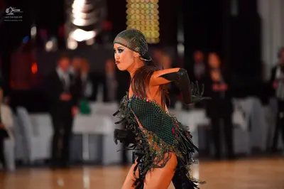 Dancesport competitor: Female dancer: dark green and black latin dance dress with sequins, mesh, and fr