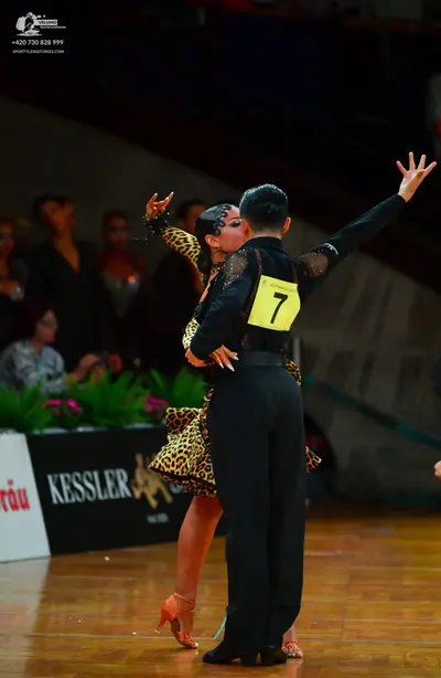 Dancesport competitor: Male dancer: black long-sleeved top with sheer/lace details on the arms and blac