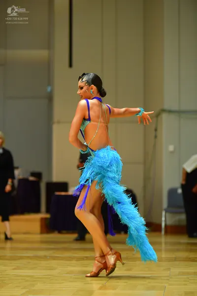 Dancesport competitor: Female dancer: turquoise Latin dress with long, fluffy feather trim, backless st