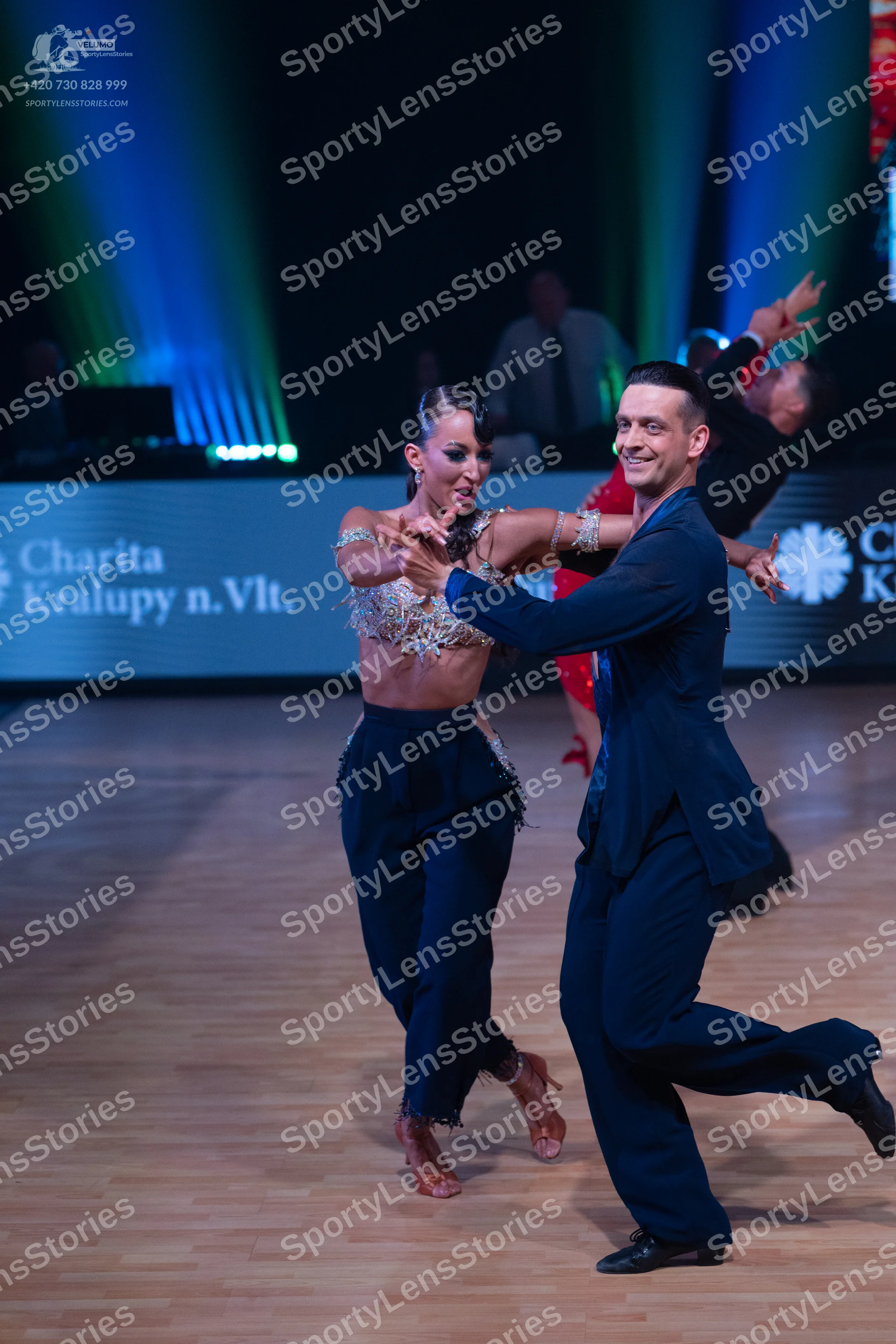 Dancesport competitor: Female dancer: silver sequined crop top and navy blue high-waisted trousers with