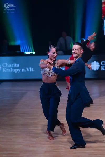 Dancesport competitor: Female dancer: silver sequined crop top and navy blue high-waisted trousers with
