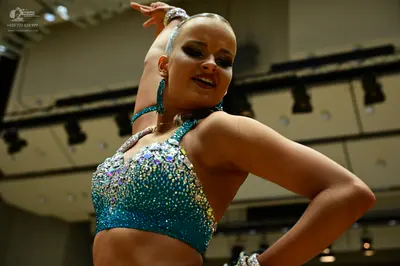 Dancesport competitor: Female dancer: teal/blue-green sequined halter-style crop top with heavy rhinest