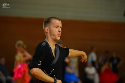 Dancesport competitor: Male dancer: black long-sleeved Latin dance top with a deep V-neck and silver de