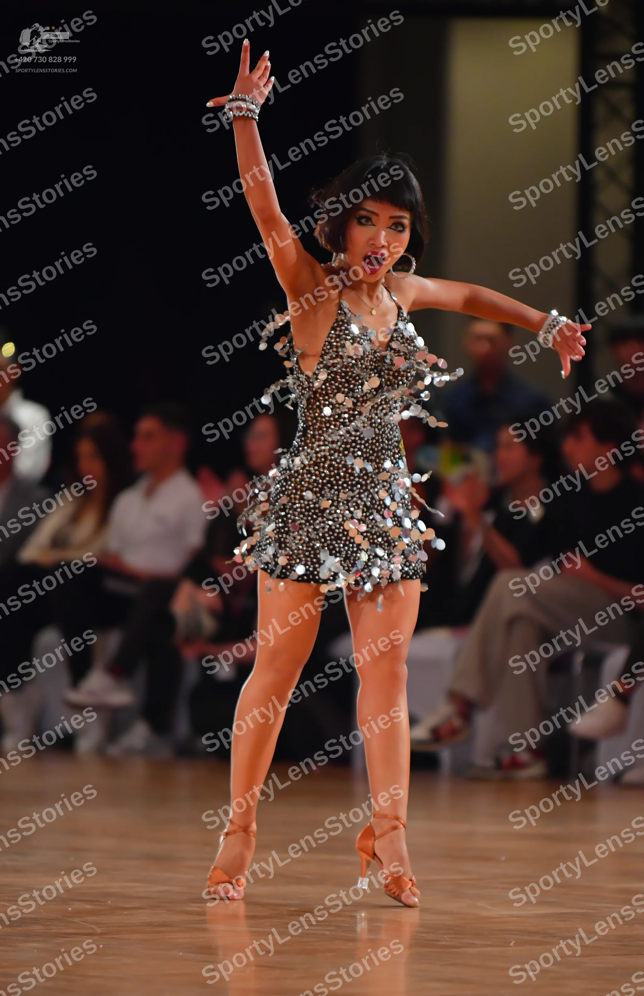 Dancesport competitor: Female dancer: dark grey or black latin dress embellished with large, reflective
