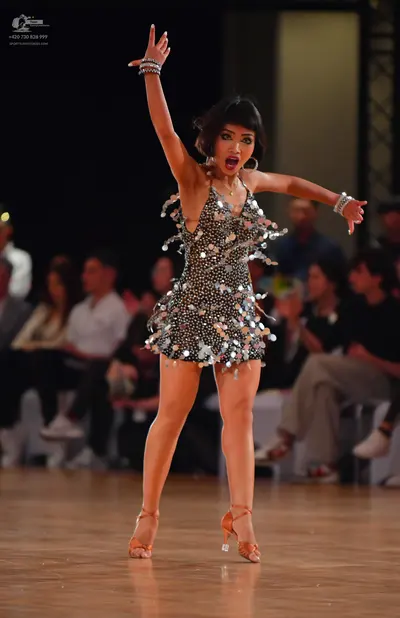 Dancesport competitor: Female dancer: dark grey or black latin dress embellished with large, reflective
