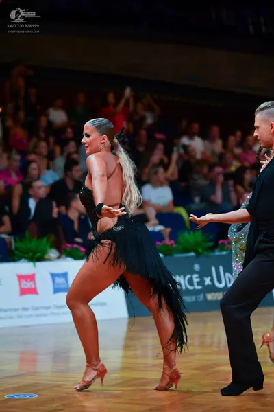 Dancesport competitor: Female dancer: black Latin dance costume with a black bodice and a skirt featuri