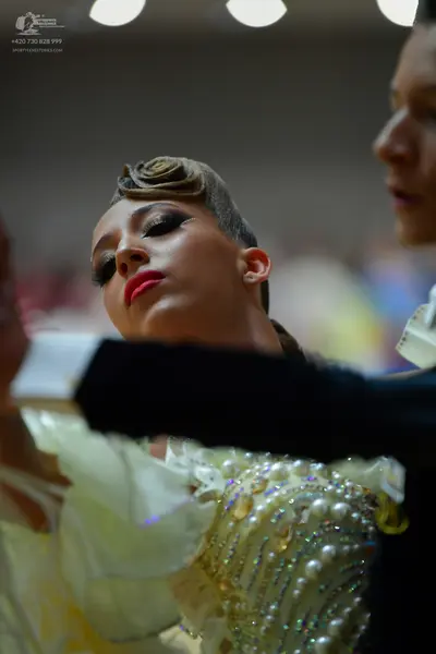 Dancesport competitor: Female dancer: off-white ballroom dress heavily embellished with pearls, rhinest