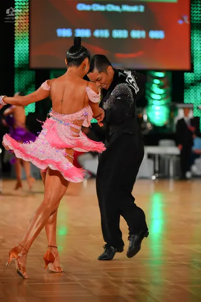 Dancesport competitor: Female dancer: pink/salmon Latin dress with sequins and a layered, flowing skirt