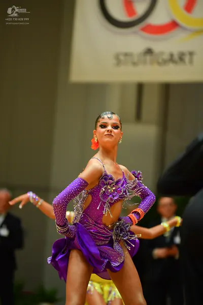 Dancesport competitor: Female dancer: purple latin dress with sequins, rhinestones, and cutouts, and la