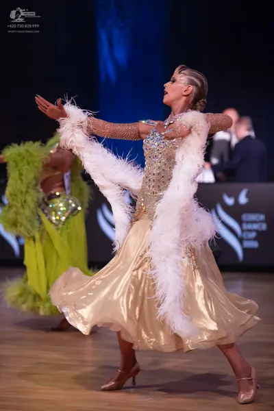Dancesport competitor: Female dancer in foreground: gold ballgown with a sequin and crystal-encrusted b
