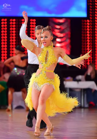 Dancesport competitor: Female dancer: yellow latin dress with sequins and yellow feather fringe, long y