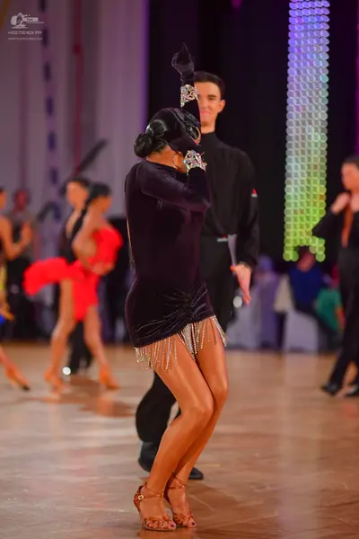 Dancesport competitor: Female dancer: dark purple velvet latin dress with a draped skirt and silver fri