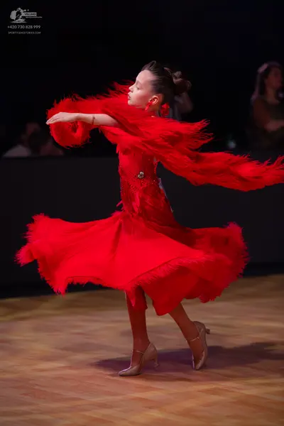 Dancesport competitor: Female dancer: red latin dress with feathery fringe on the sleeves and skirt, wi