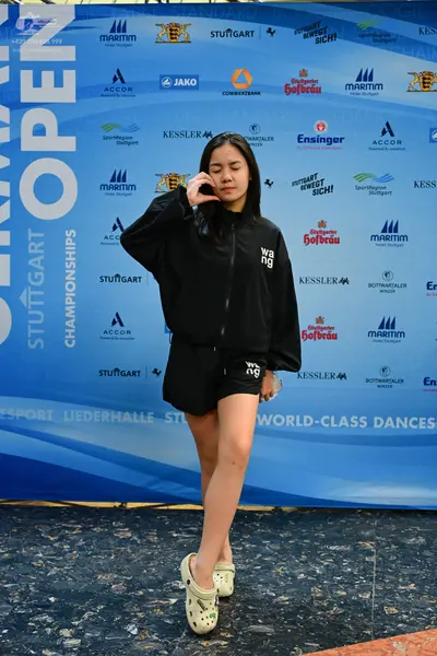 Dancesport competitor: Female dancer: black sweatshirt with "wang" written in white, black shorts with 
