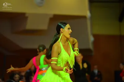 Dancesport competitor: Female dancer in foreground: lime green latin dress with fringe and matching arm