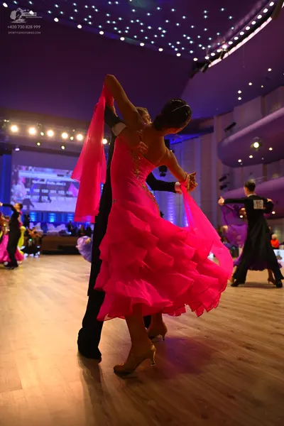 Dancesport competitor: Female dancer: bright pink Latin dress with many ruffled layers