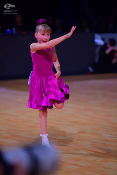 Dancesport competitor: Female dancer: magenta satin sleeveless dress with a flared skirt, a small pink 