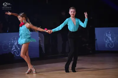 Dancesport competitor: Female dancer: light blue latin dress with fringe and a red flower accessory at 