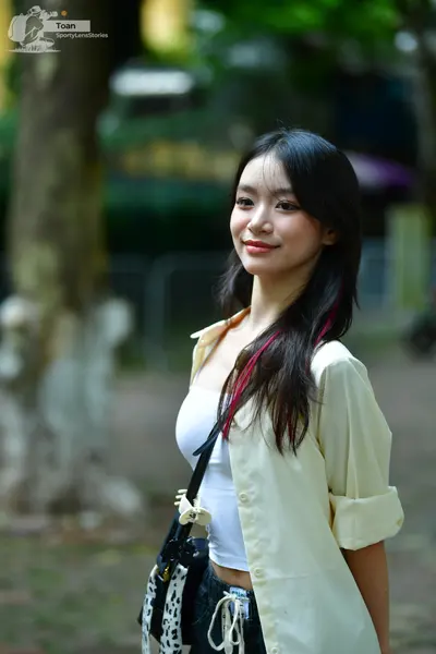 Dancesport competitor: Female dancer: white sleeveless top, light yellow unbuttoned shirt, and dark pan