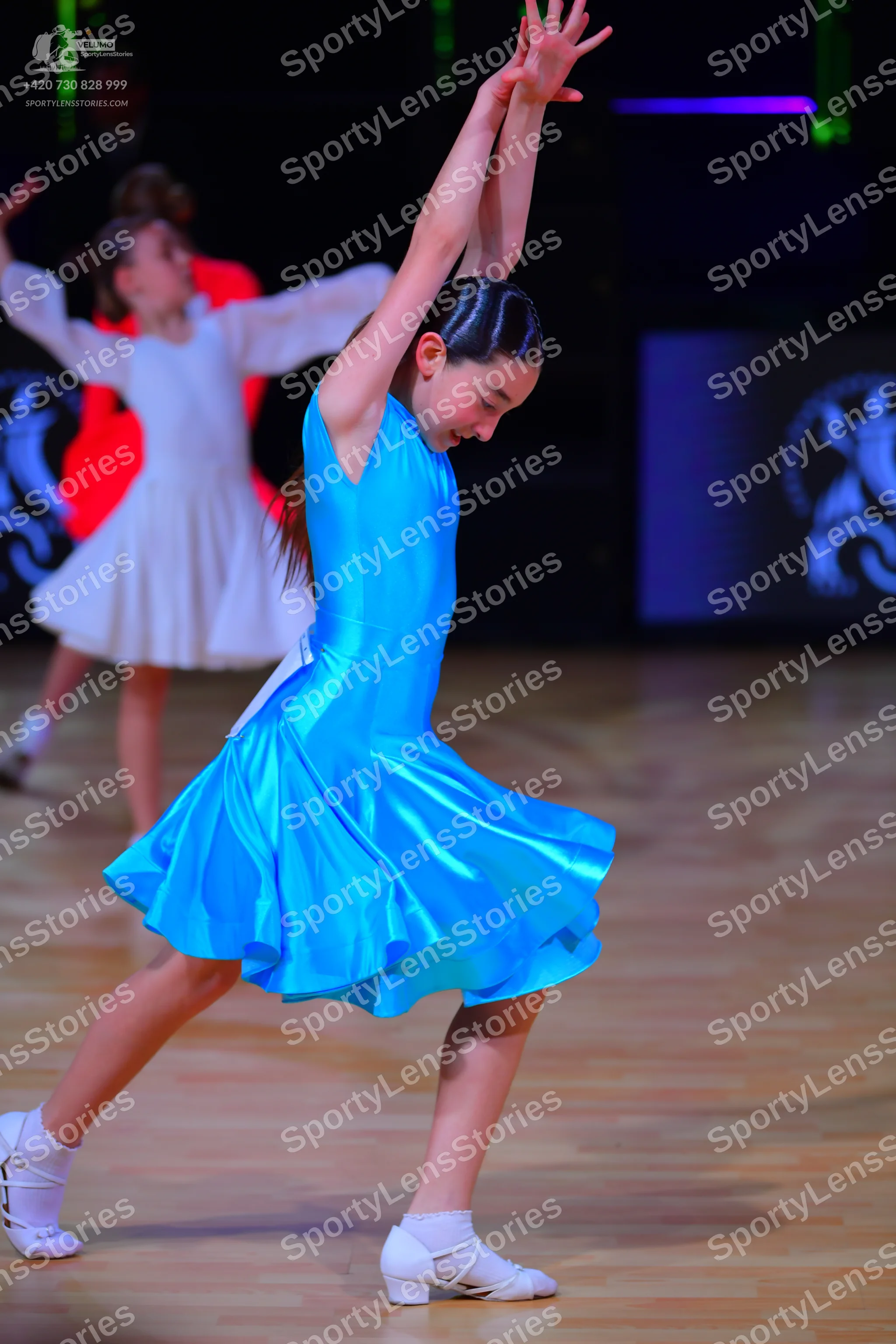 Dancesport competitor: Female dancer 1: blue satin sleeveless Latin dress with a flared skirt and white