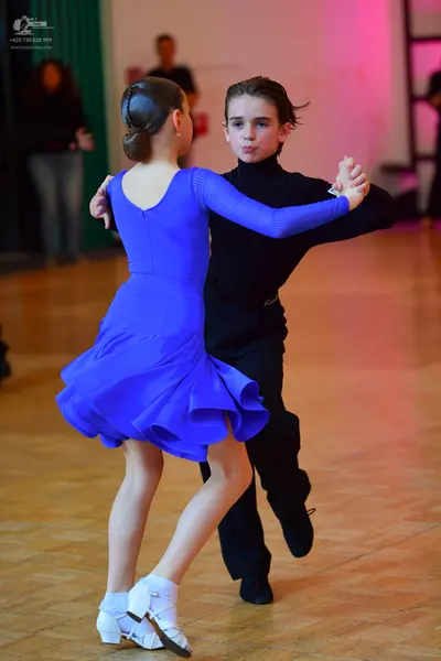Dancesport competitor: Female dancer: blue long-sleeved latin dress with a flared skirt and white dance