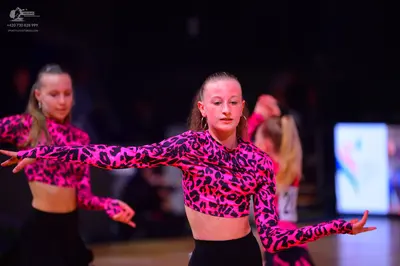 Dancesport competitor: Female dancer: pink and black leopard print long-sleeved crop top and black high