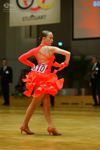 Dancesport competitor #810: Female dancer: bright orange long-sleeved Latin dress with an open back, criss-c