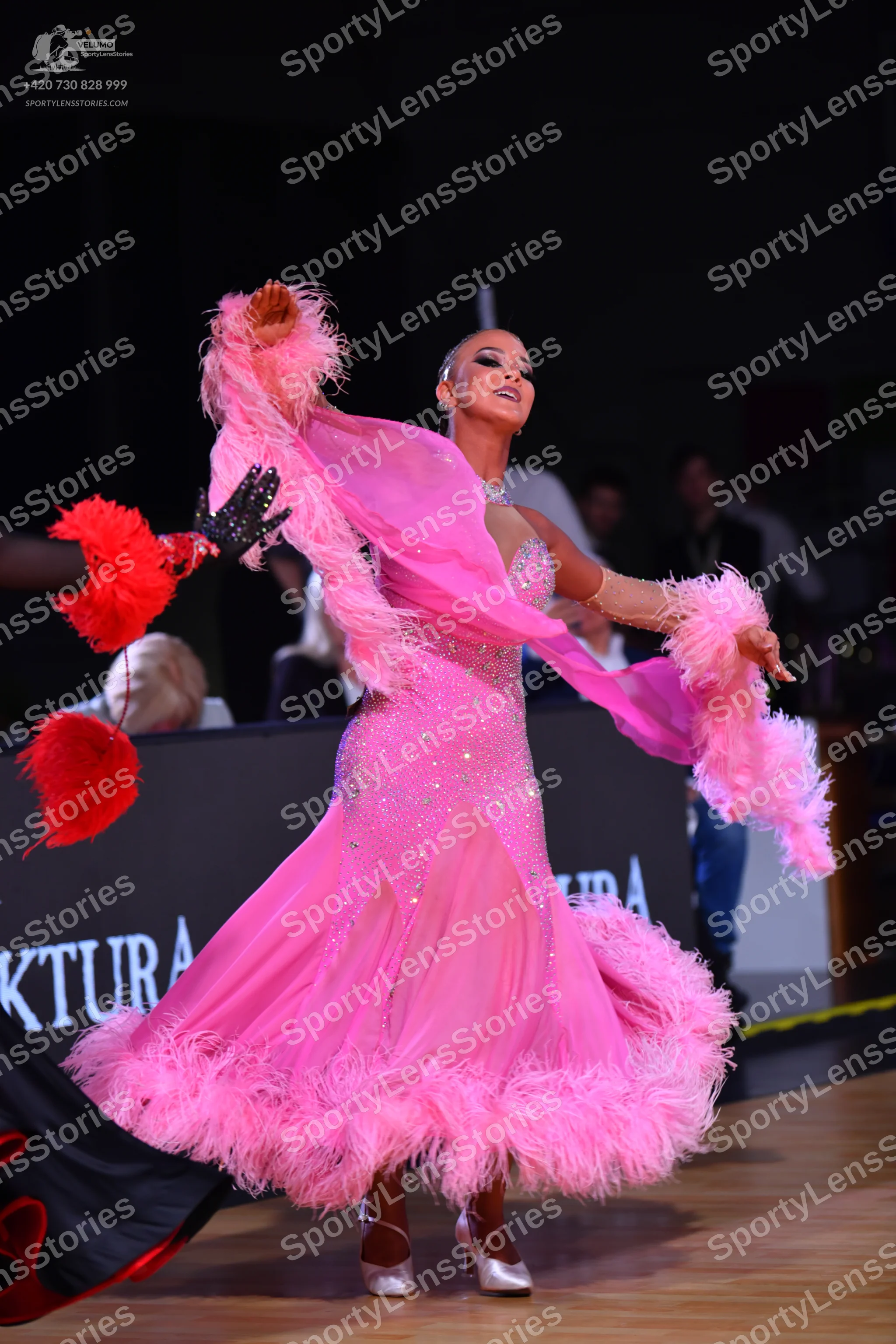 Dancesport competitor: Female dancer: pink ballroom dress with sheer, flowing sleeves and a voluminous