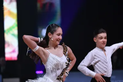 Dancesport competitor: Female dancer: white latin dress with fringe and leopard print detail, wearing w