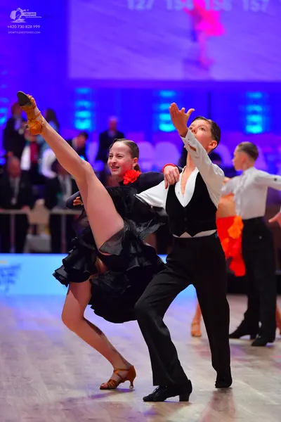 Dancesport competitor: Female dancer: black latin dance dress with a voluminous, ruffled skirt and a re