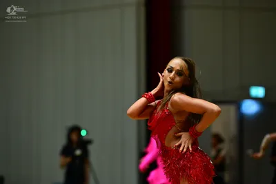 Dancesport competitor: Female dancer: red latin dress with fringe and cutouts, with matching red wristb