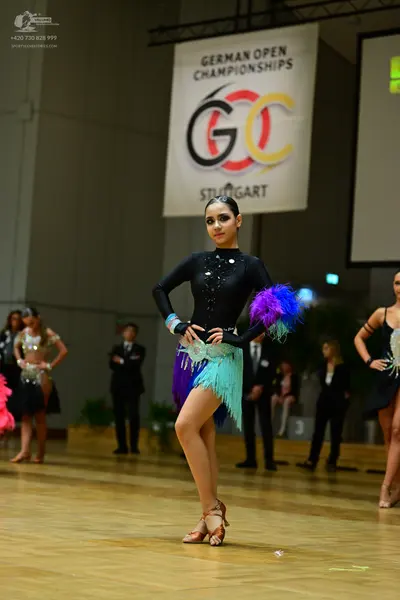 Dancesport competitor: Foreground female dancer: black long-sleeved Latin dress with silver/sequin wais