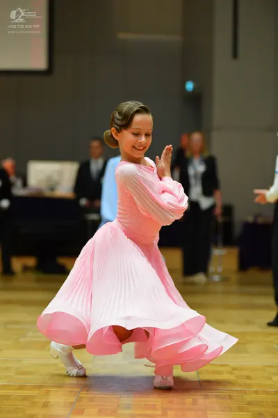 Dancesport competitor: Female dancer: light pink, long-sleeve ballroom dress with a pleated texture and