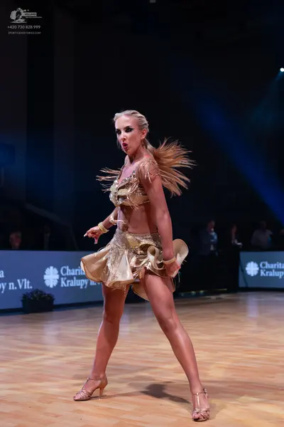 Dancesport competitor: Female dancer: champagne-colored Latin dance costume featuring a fringe skirt an