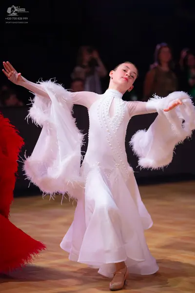Dancesport competitor: Female dancer: white standard dress with long sleeves and large, voluminous whit