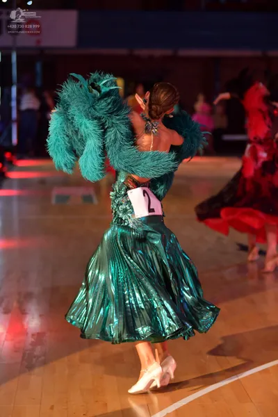Dancesport competitor: Female dancer: emerald green metallic ballroom dress with a large, voluminous em