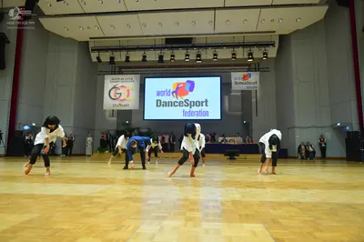 Dancesport competitor: Five dancers are visible in the foreground performing a choreography