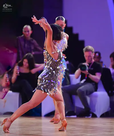 Dancesport competitor: Female dancer: dark Latin dress covered in large, shiny silver sequins or metall
