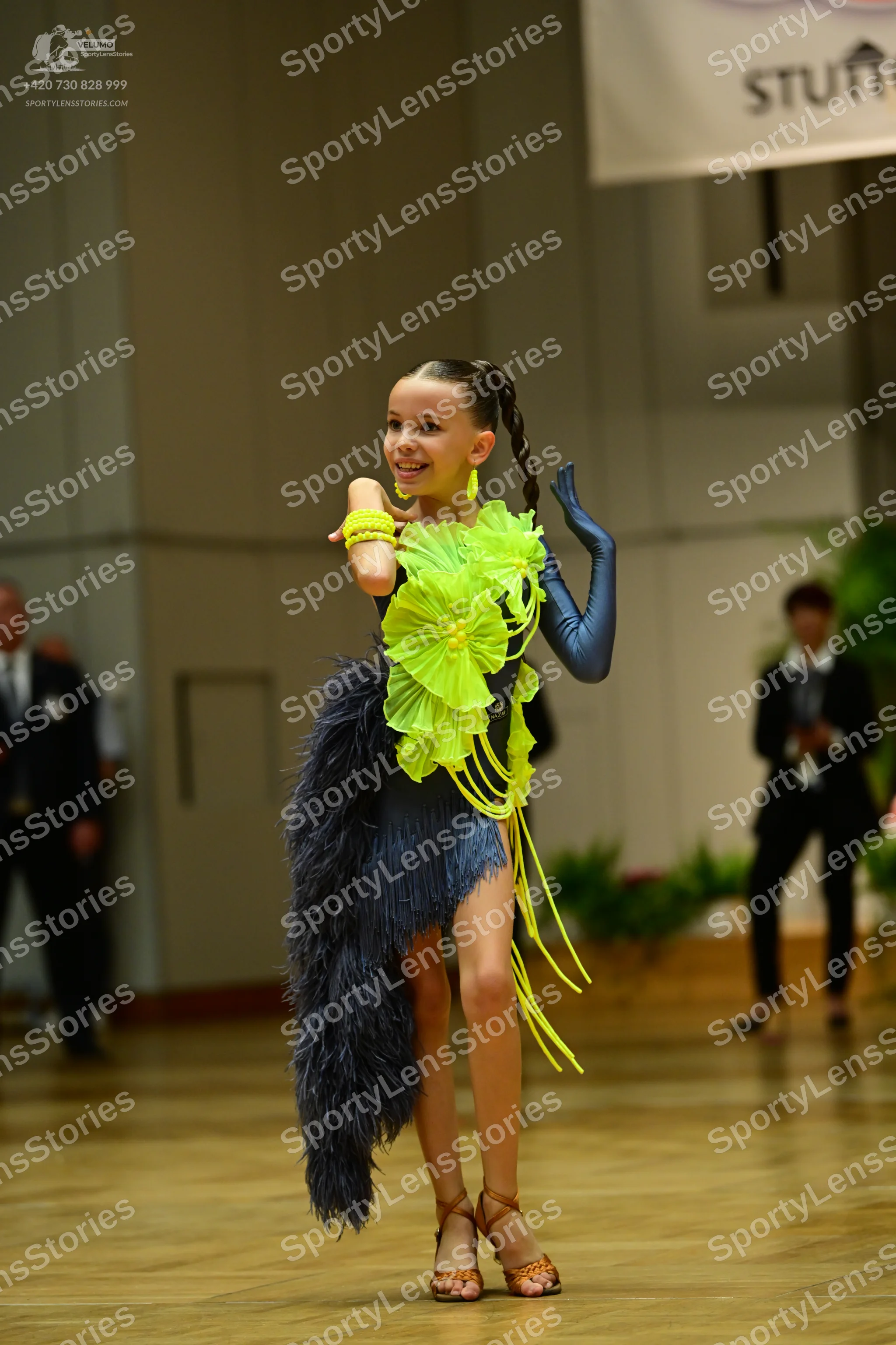 Dancesport competitor: Female dancer: dark blue latin dress with a large lime green fabric ruffle at th