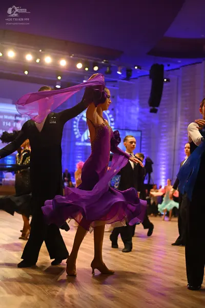 Dancesport competitor: Female dancer (center): purple latin dress with a flowing, ruffled skirt and a s