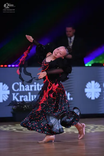 Dancesport competitor: Female dancer: black ballgown with red flame patterns, long sleeves, and a volum