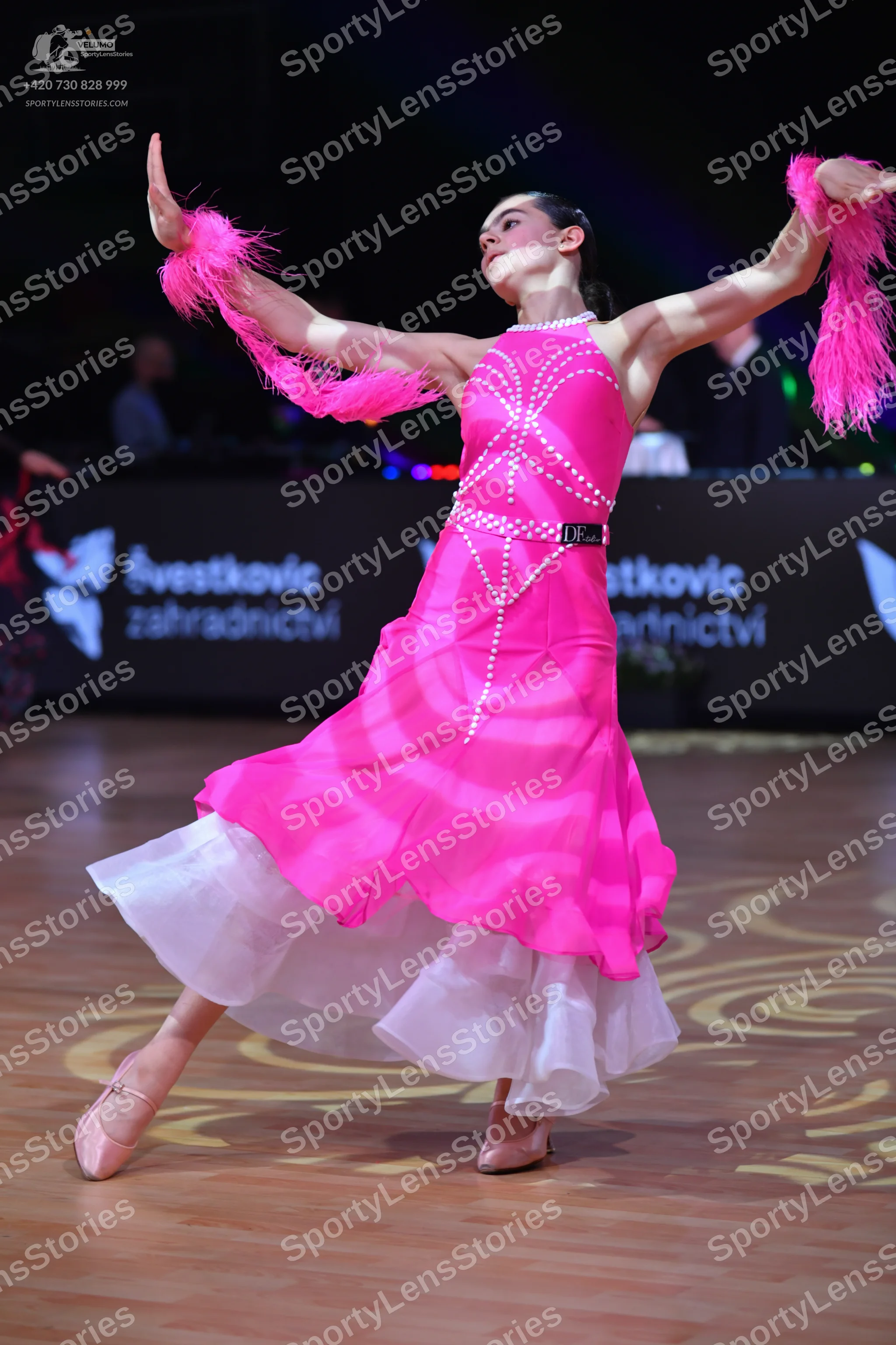 Dancesport competitor: Female dancer: bright pink ballroom dress with vertical rhinestone detailing on