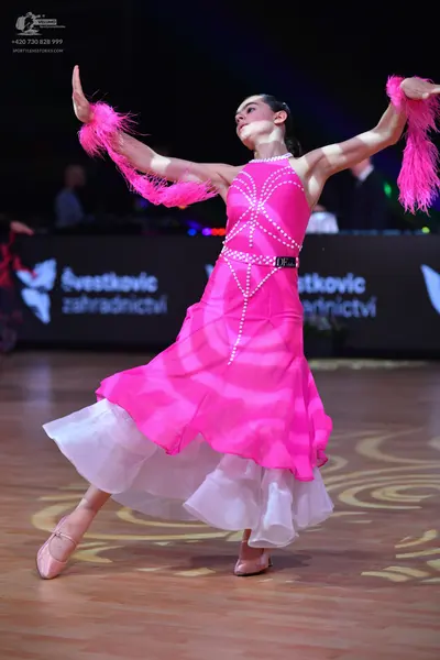 Dancesport competitor: Female dancer: bright pink ballroom dress with vertical rhinestone detailing on 
