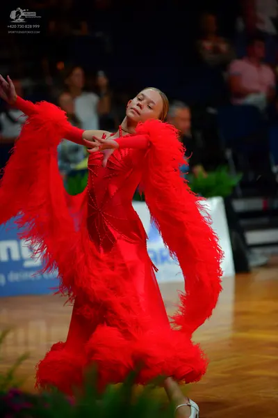 Dancesport competitor: Female dancer: red latin dress with large, voluminous red feathered sleeves and 