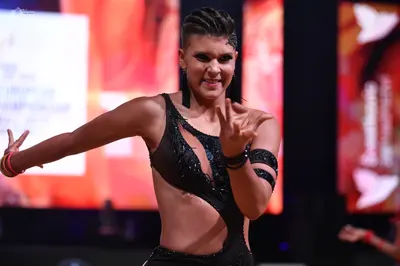 Dancesport competitor: Female dancer: black latin dance costume with cutouts and sequin embellishments,