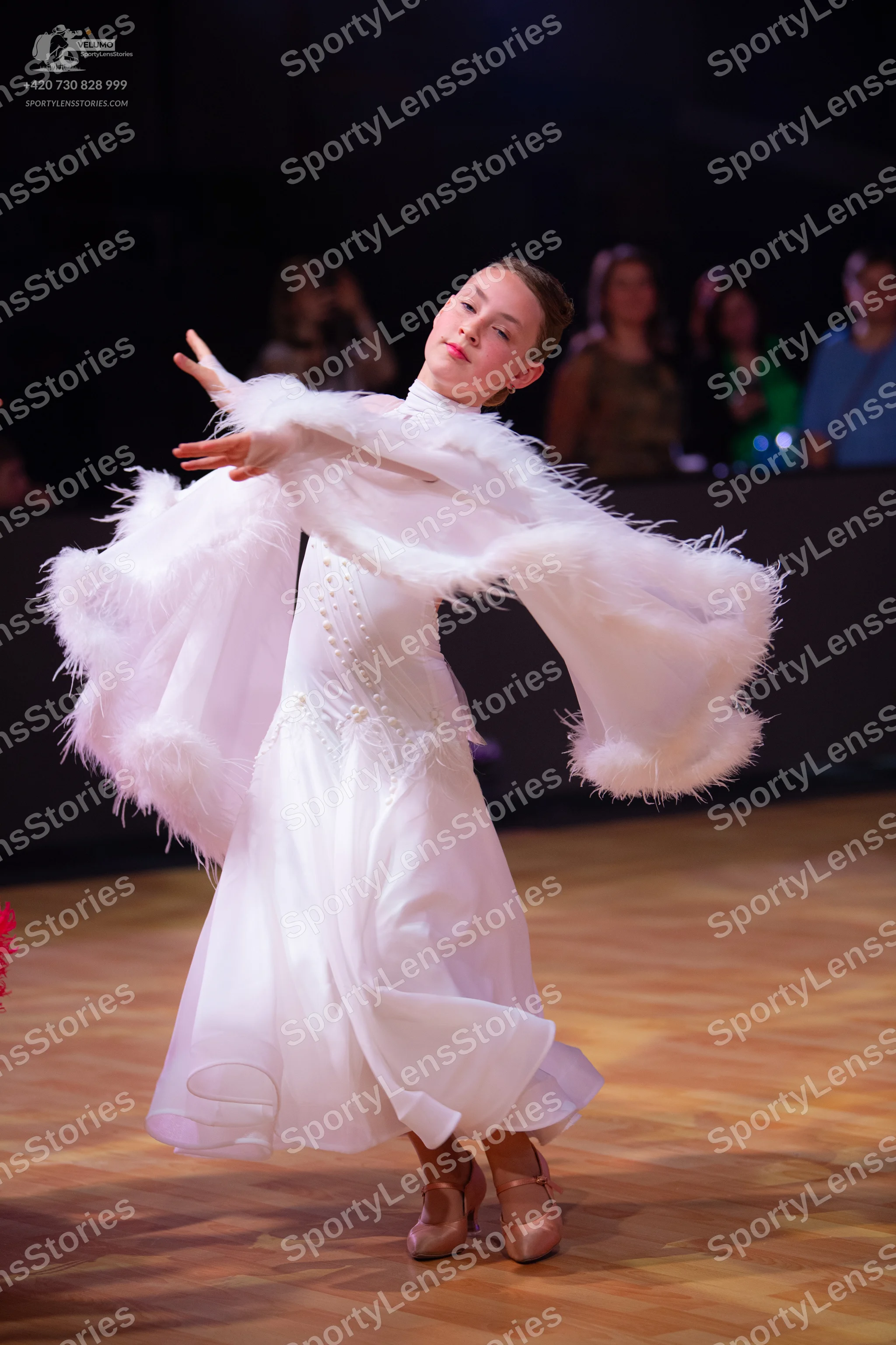Dancesport competitor: Female dancer: white ballroom gown with large, voluminous, feathery white sleeve